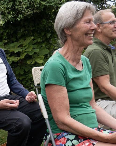 Een lachende deelnemer op een stoel in de tuin