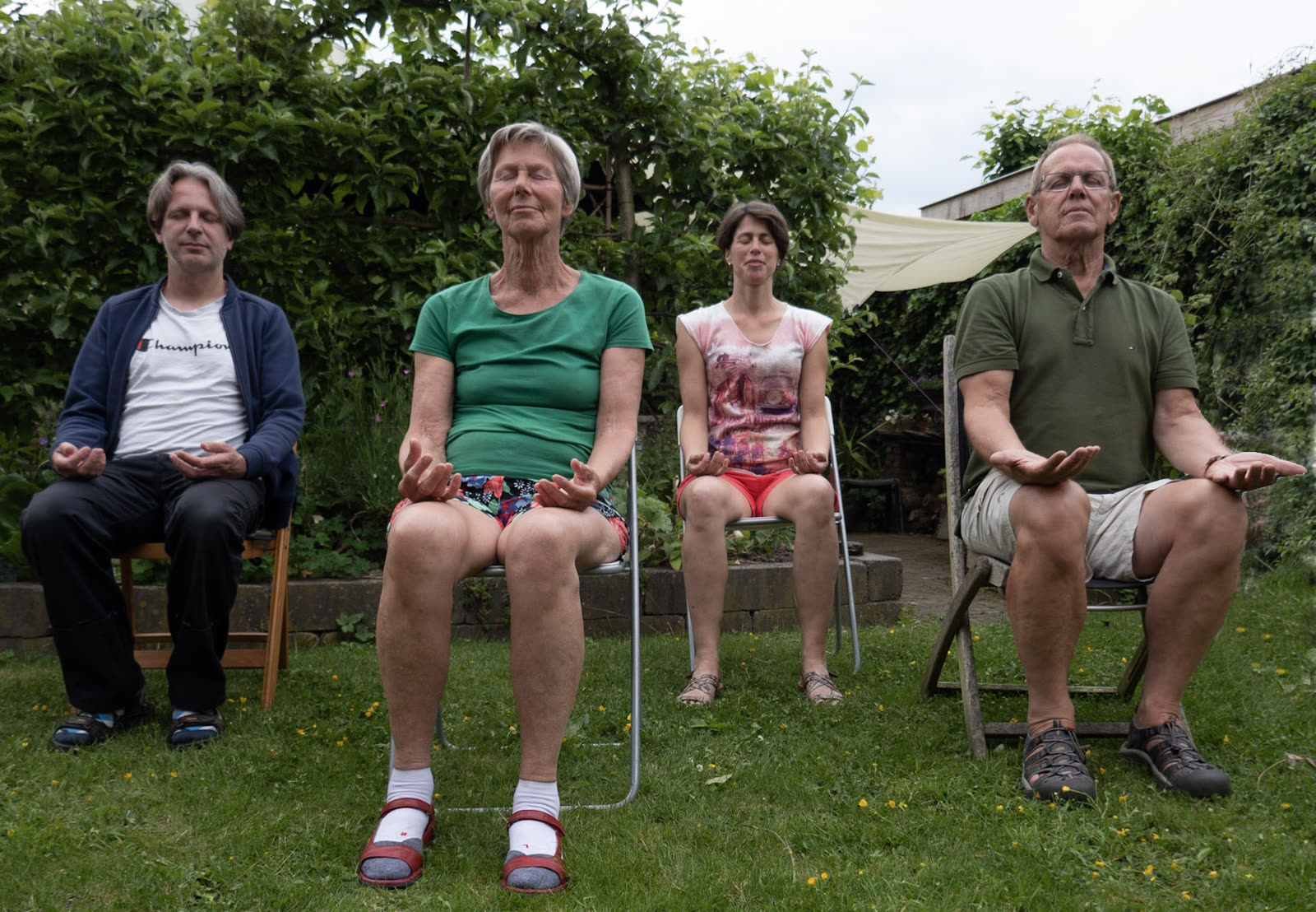 Vier mensen zitten op een stoel in een tuin en mediteren
